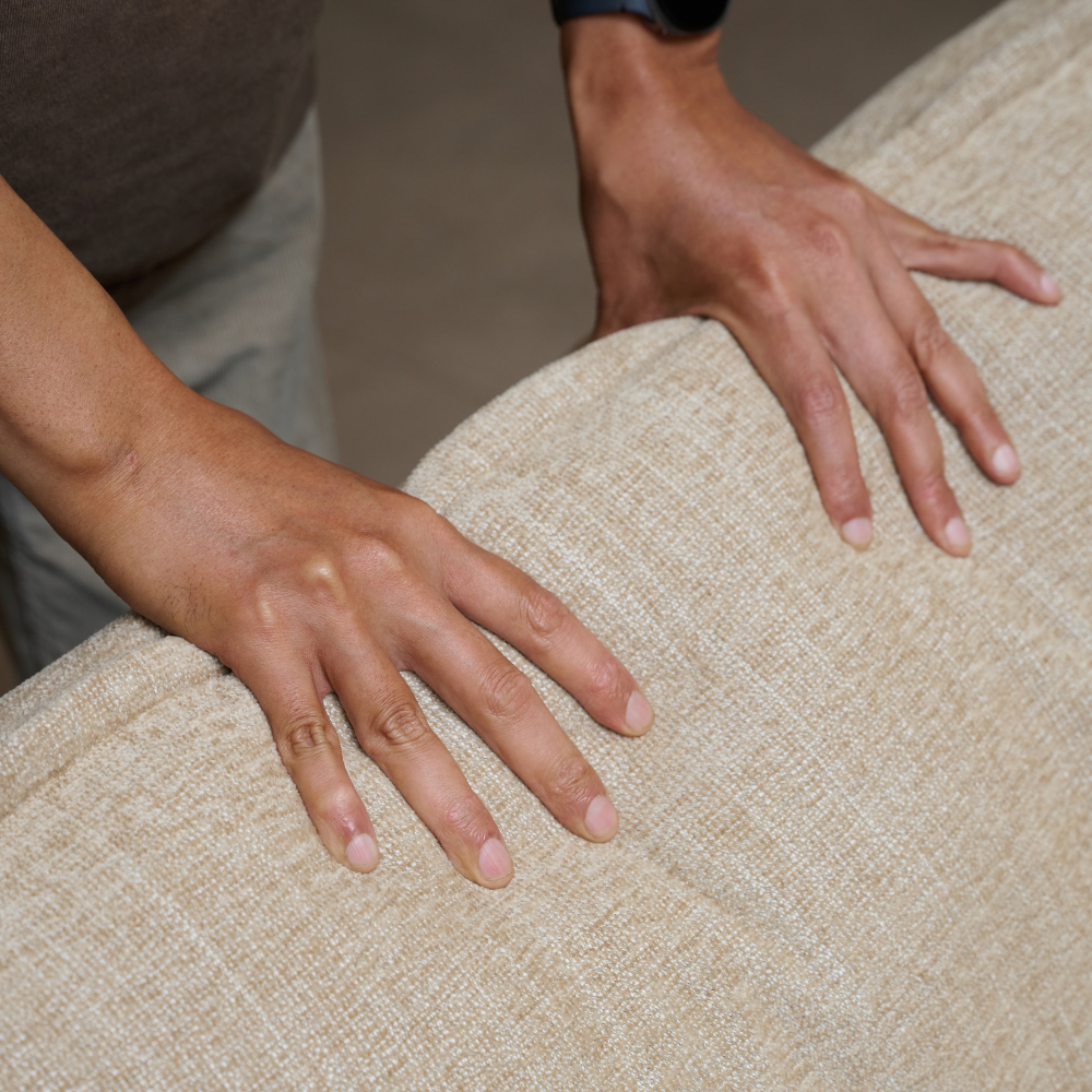 Close-up of a person's hands resting on the textured of ELLE Home Amelie Armchair Lemon Ultra-Soft Weave.